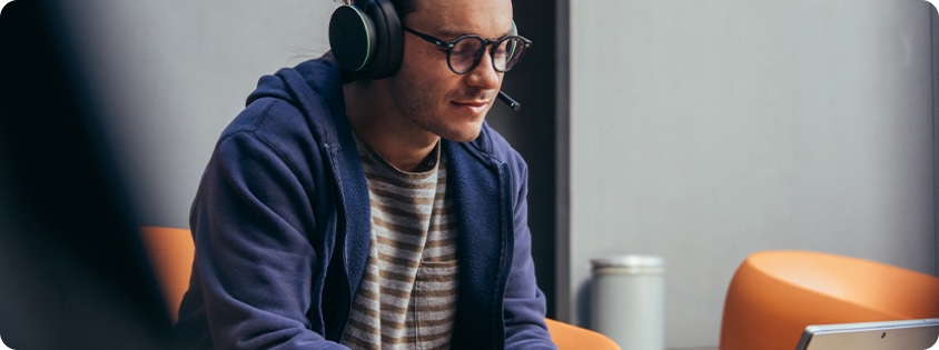 Man gaming with a headset and controller on a Microsoft laptop